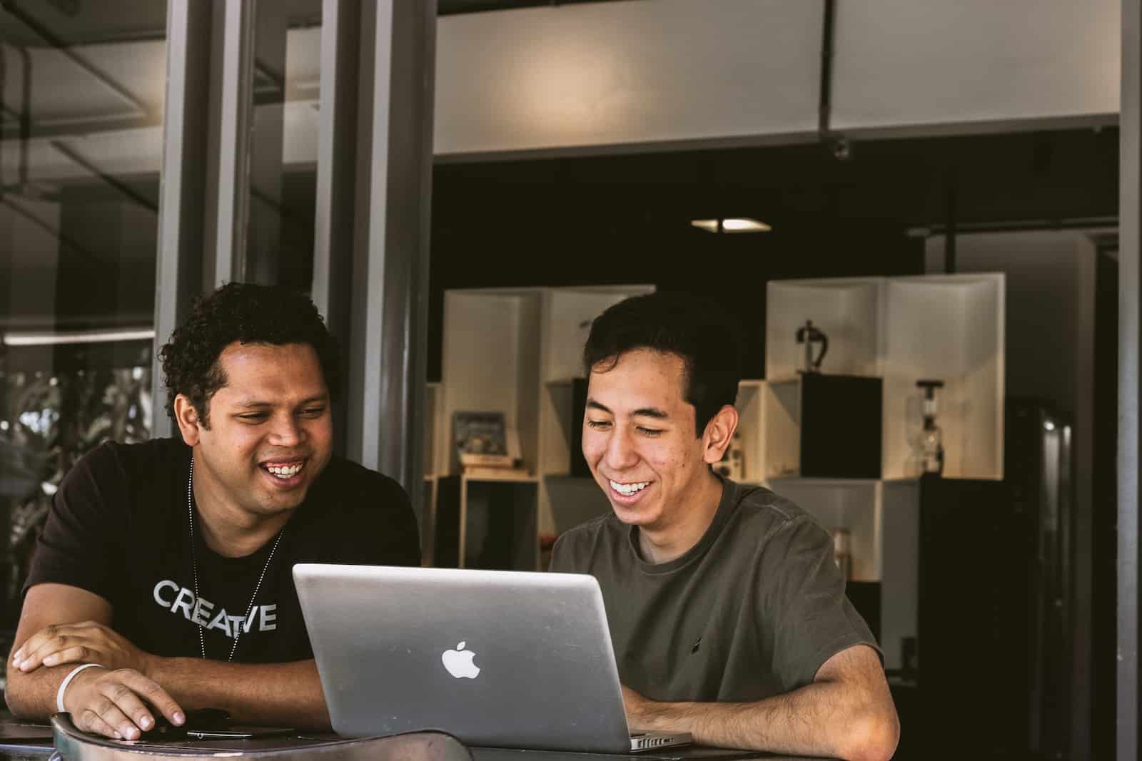Business Mentor and Mentorship. Two men smiling and looking at a laptop in a startup funding meeting.