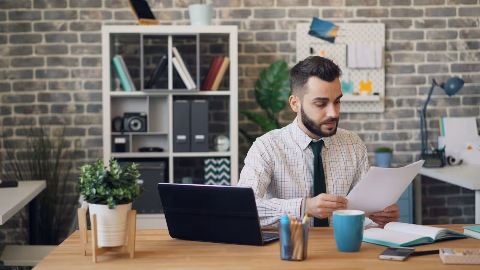 A man sitting at a desk in front of a laptop ensuring effective construction contract management.