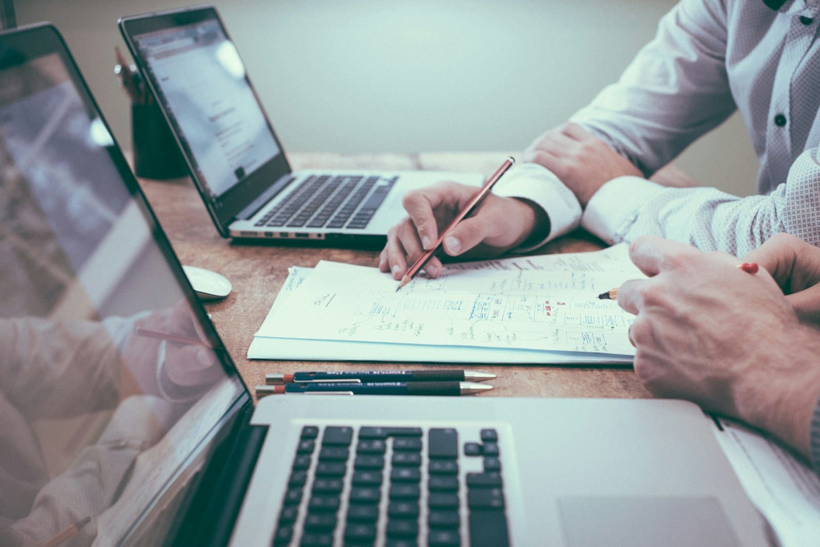 Person holding pencil near laptop computer. Small business management constultant