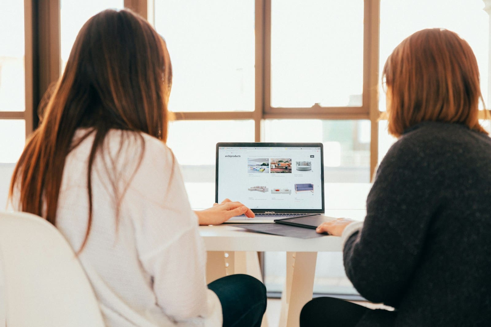 Two women talking while looking at laptop computer. Small Business Management Consultant
