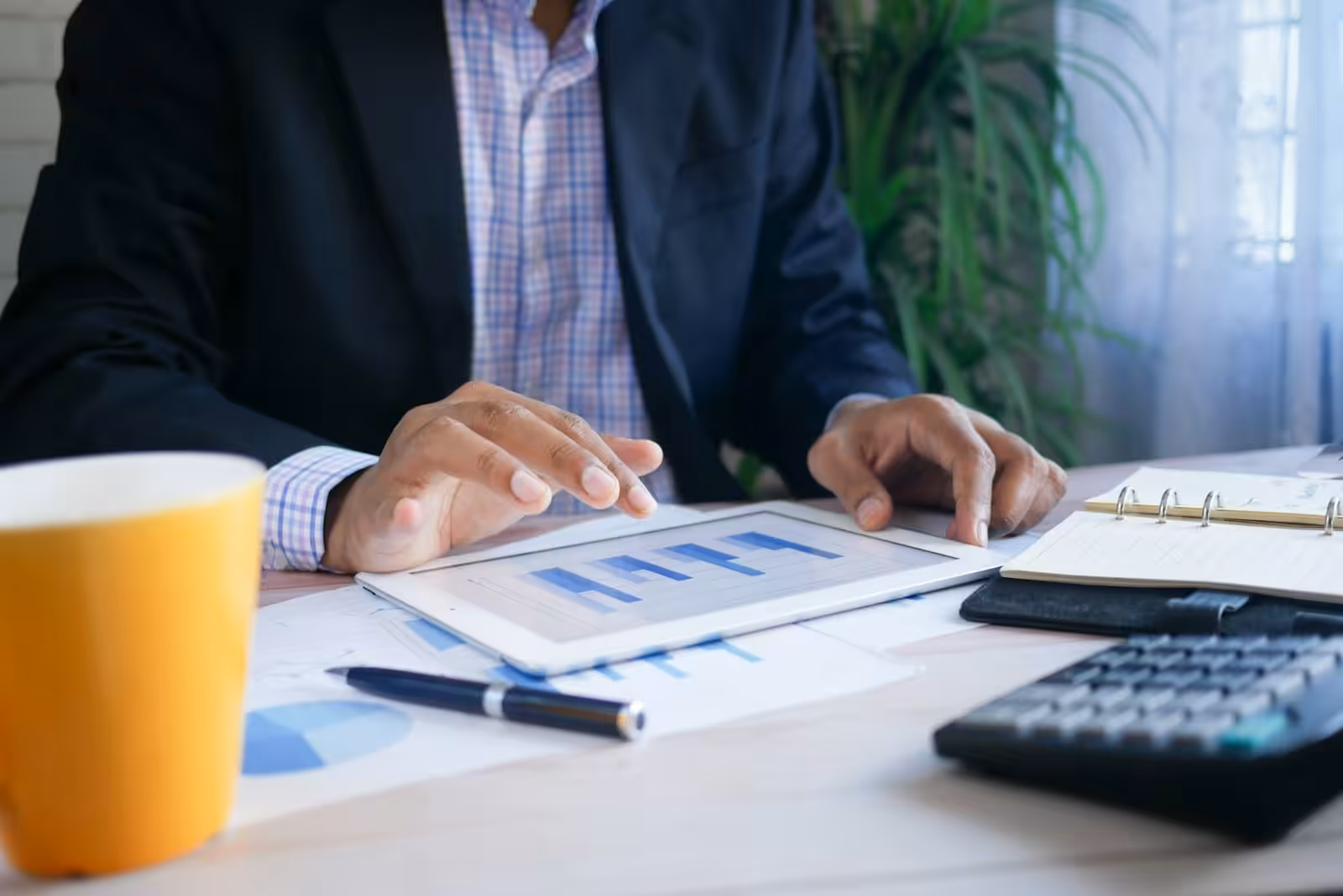 Person in black suit jacket holding white tablet computer. How to improve cashflow in a business