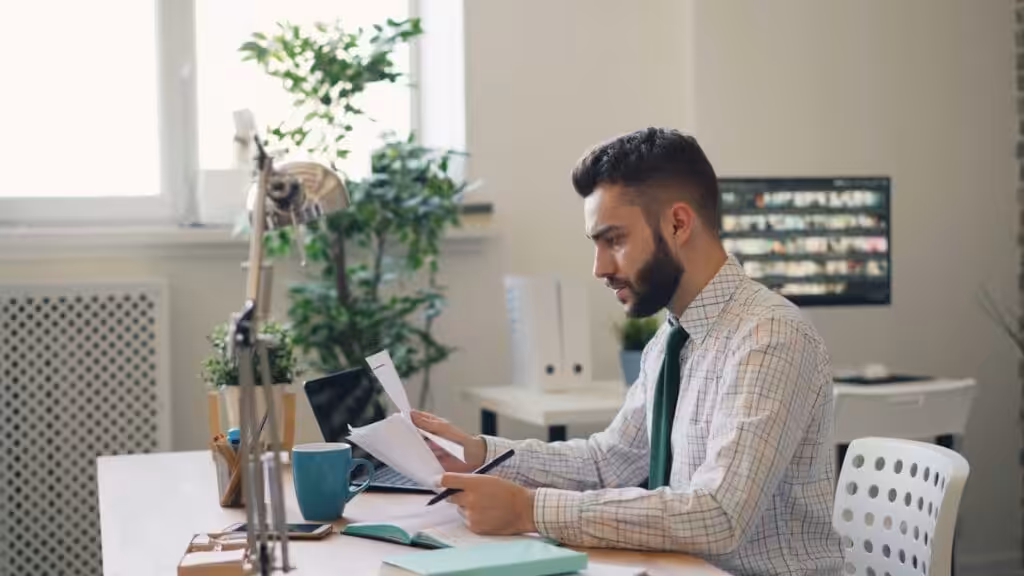 A man sitting at a desk with a laptop and Construction Contract carrying out Contract Management