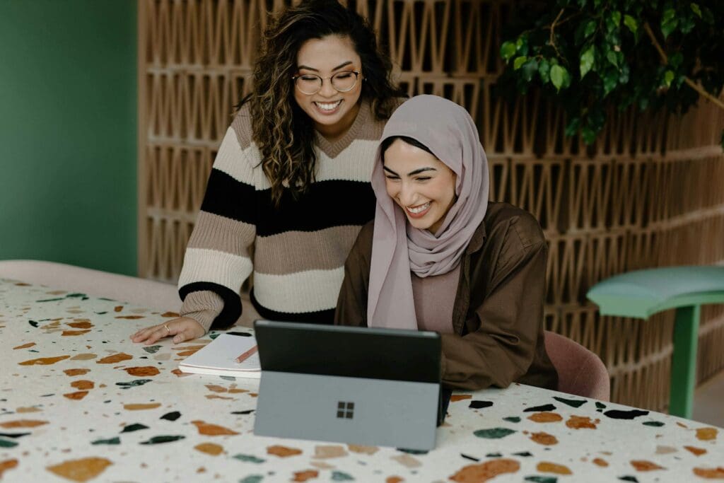 Business Loan Calculator - Should My Business Take Out A Loan? 4 Two women sitting at a table with a laptop. Business Loan Consultant. Document Review