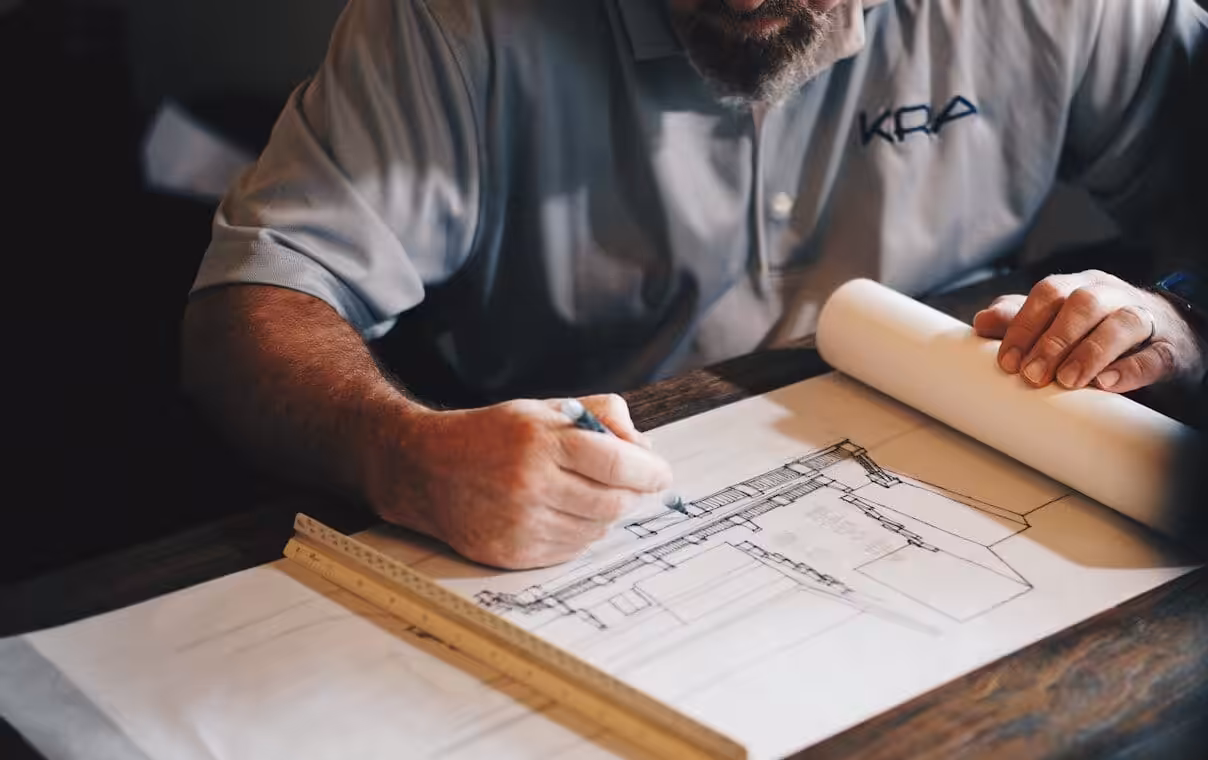 An architect working on a draft with a pencil and ruler. Design and construct vs Construct only