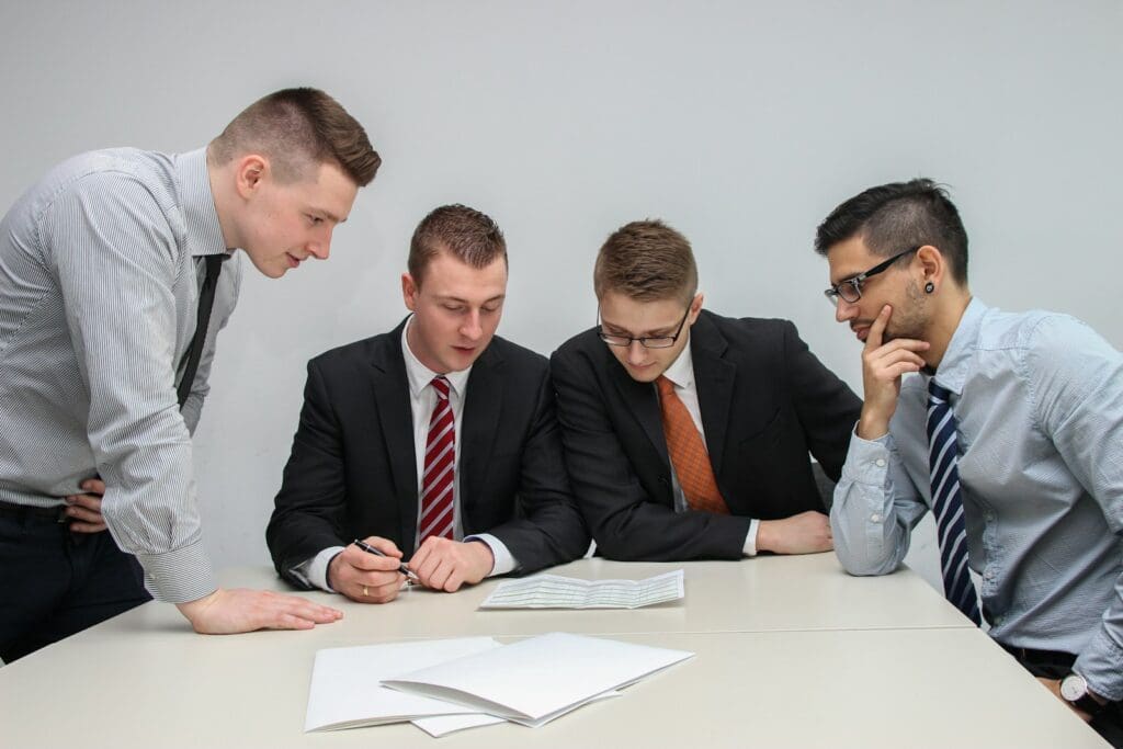 Business Loan Calculator - Should My Business Take Out A Loan? 3 Bankers and business owners looking at the papers on the table. Business Loan Calculator. Construction Contract Review