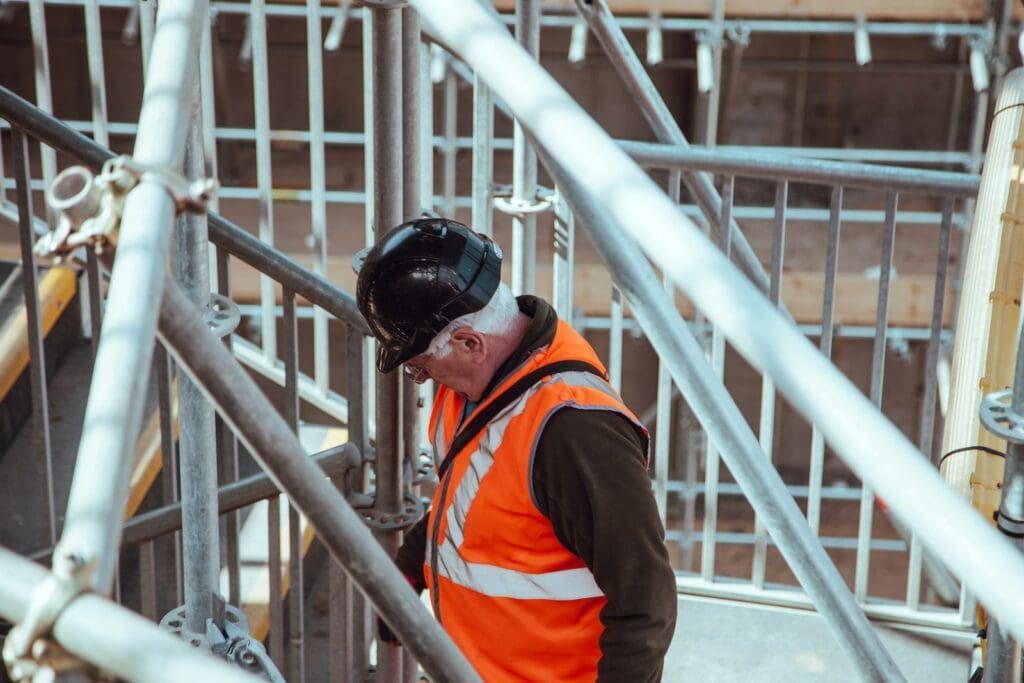 Business Loan Calculator - Should My Business Take Out A Loan? 5 Construction business owner standing under scaffoldings. Business Loan Calculator. Business Growth Strategist