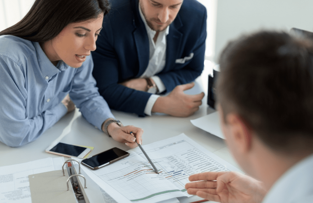 Contract Review 12 Businessman and business advisors reviewing a printed chart with graphs and data. Business Advice. Contract Review