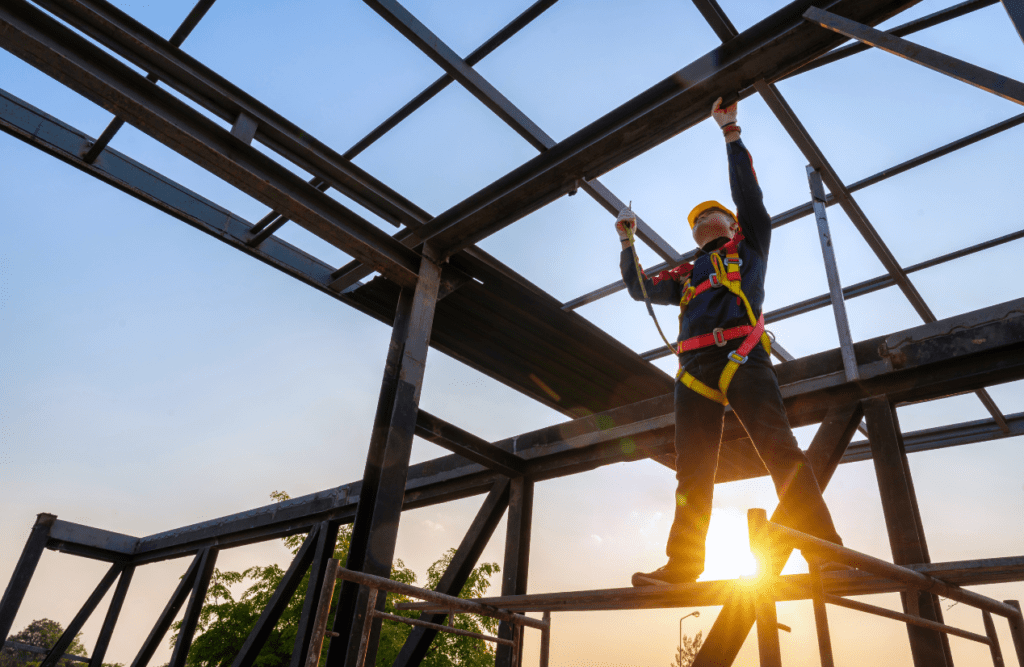 Man wearing safety gear stands on a scaffold. Risk Management in Construction Projects