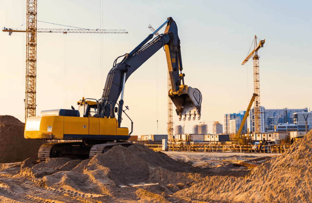 Tower cranes and excavator at construction site. Risk Management in Construction Projects