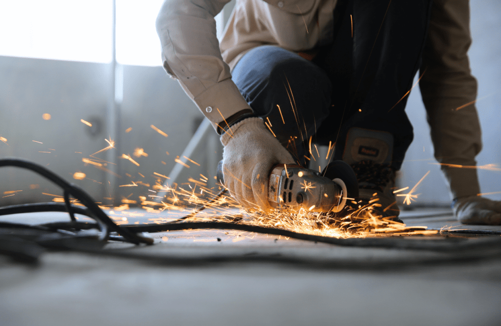 Construction worker uses grinder to cut a metal cable. Risk Management in Construction Projects