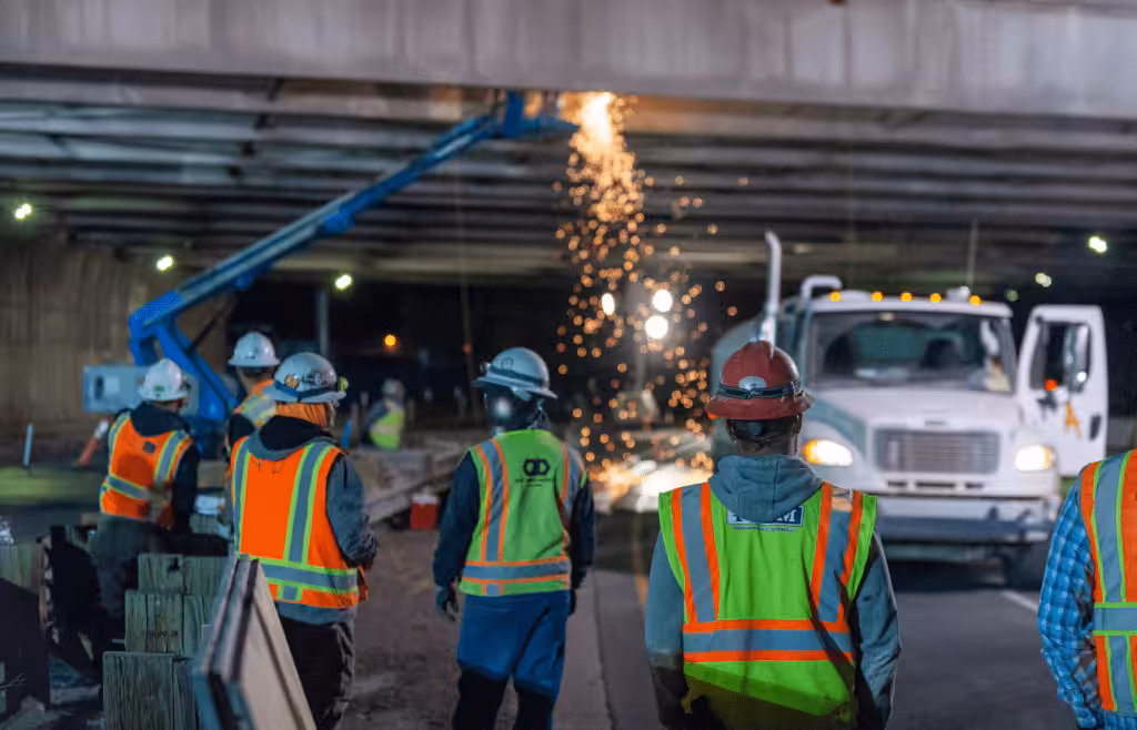 Construction workers are welding under a bridge. DLP Meaning
