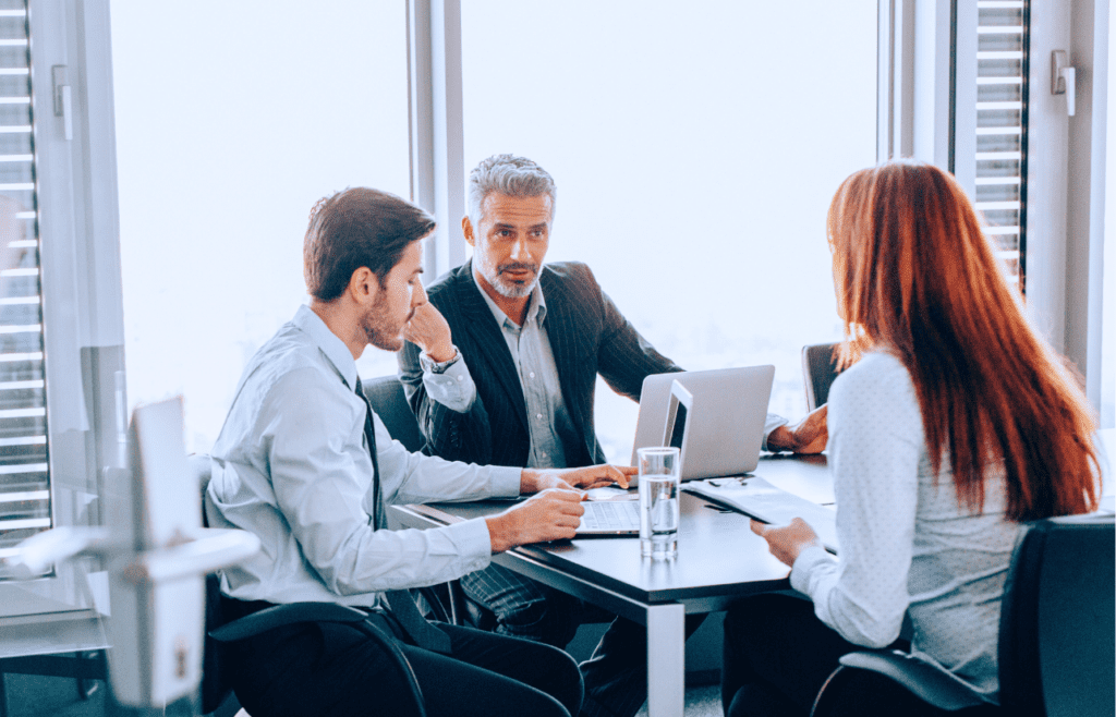 Management Consulting – A Straightforward Guide for Australian Business Owners 18 Threebusiness individuals gathered around an office table. Management Consulting