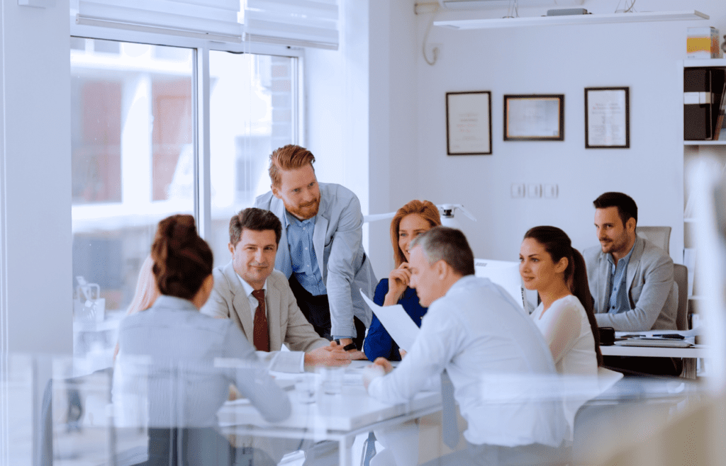 Management Consultant and clients are seated around a table. Management Consulting Companies Australia