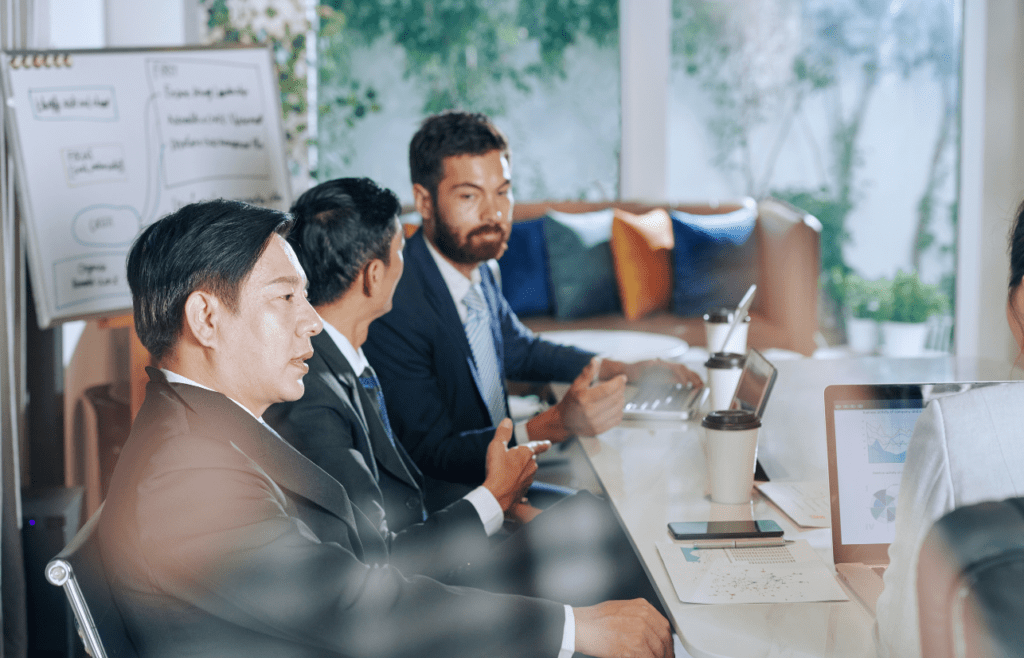 Discover Expert Management Consulting and Strategy Consulting 12 Business professionals seated around a table in a meeting room. Management Consulting and Strategy Consulting