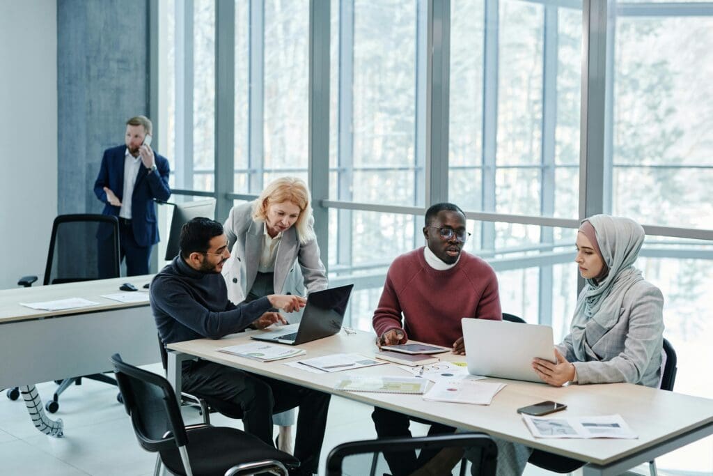 Discover Expert Management Consulting and Strategy Consulting 2 Group of individuals at a table, working on their laptops. Management Consulting and Strategy Consulting