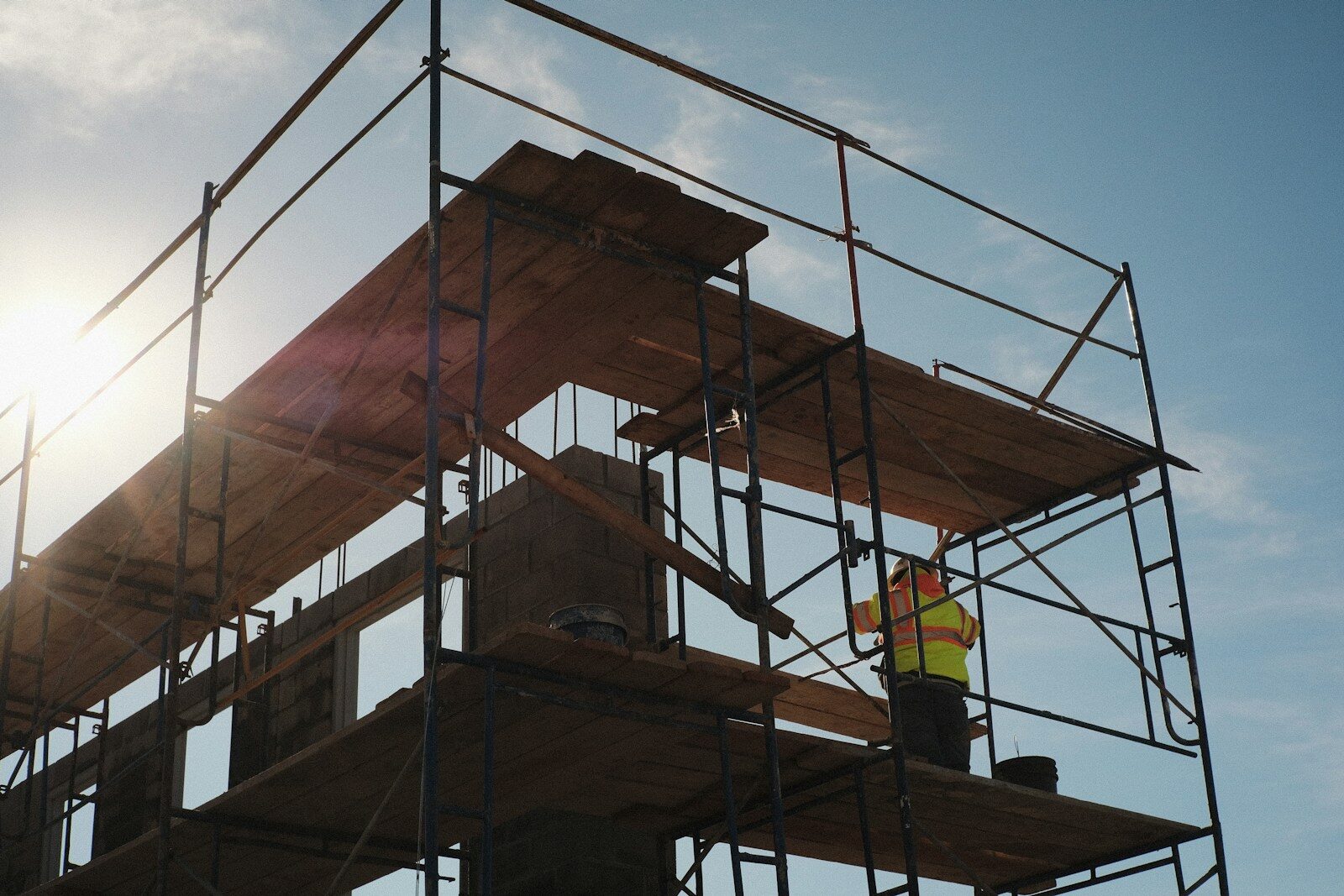 Construction worker standing on a scaffold at a construction site. Rise and fall clauses. Escalation clauses.