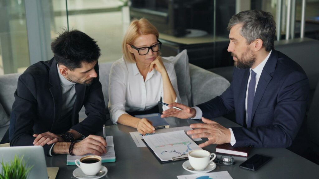 3 Shareholders sitting around a boardroom table discussing the Tag-Along and Drag-Along provisions for an upcoming share sale.