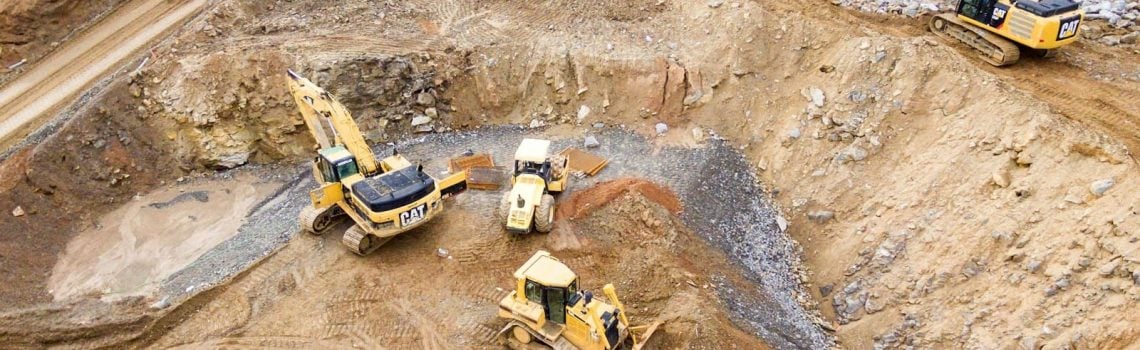 Four heavy equipment on quarry at daytime. Small Business Management Consulting
