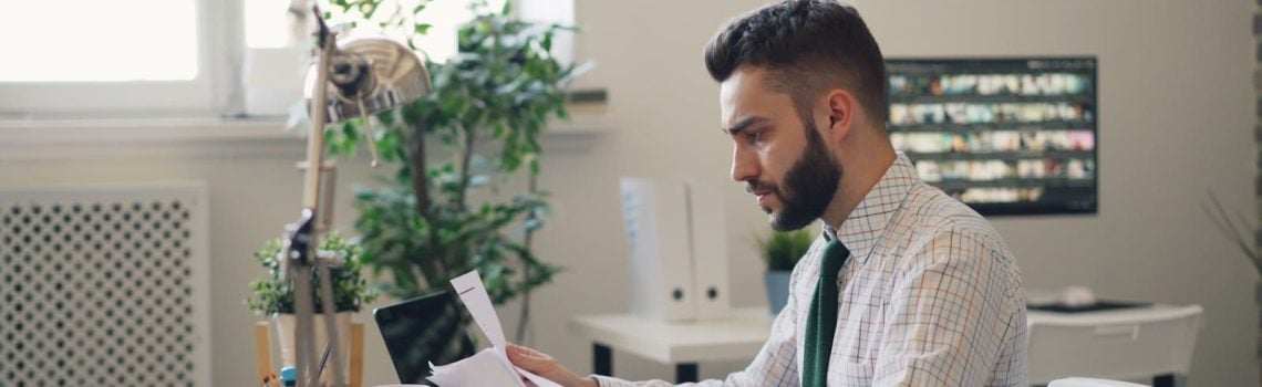 A Contracts Lawyer sitting at a desk with a laptop and pages from a contract
