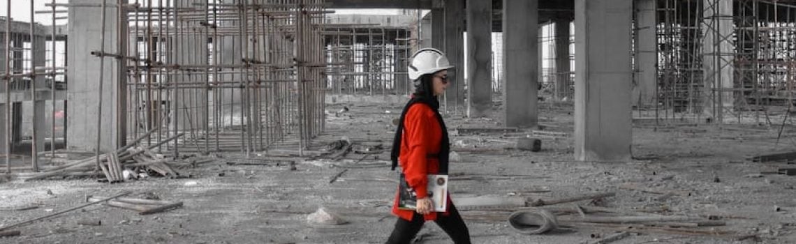 Construction Contract Administration. Woman in a red jacket walking through a construction site