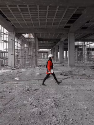 Construction Contract Administration. Woman in a red jacket walking through a construction site