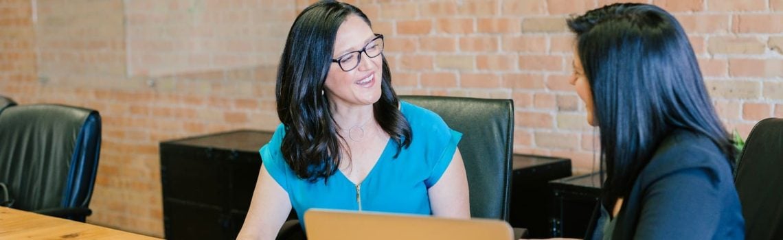 Woman in teal t-shirt sitting beside woman in suit jacket. Management Consulting and Strategy Consulting. Best Business Management Consultant Brisbane