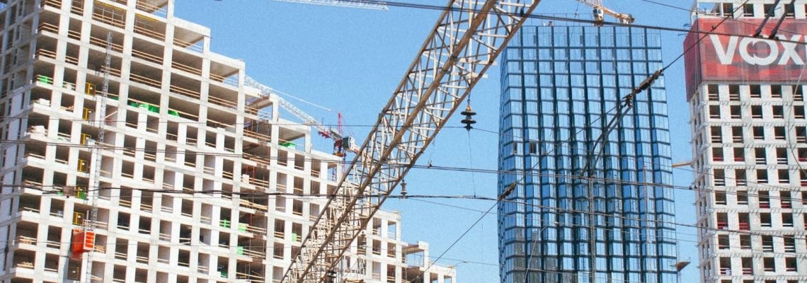 Construction site with a crane in the foreground. Time, cost and quality. Quality, time and cost. Quality, cost and time. Time, quality and cost. Time, quality, and cost. Construction Lawyers. AS2124-1992. AS2124