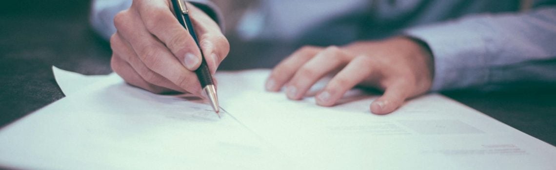 Man signing a contract. Building Contract Law. Blaze Business & Legal