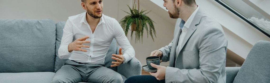 Commercial Lawyer and Business Consultant sitting on a couch talking to his client. Business Consulting at Blaze Business & Legal