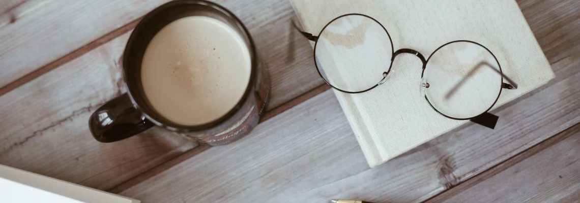 A cup of coffee near pen and glasses. Document review. Reviewing documents.