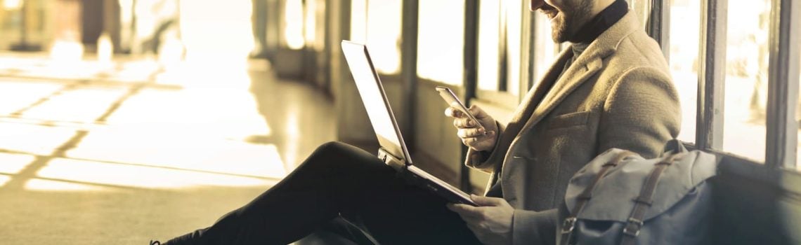 Man sitting on a couch, laughing while looking at laptop. Case Study. Business Coach