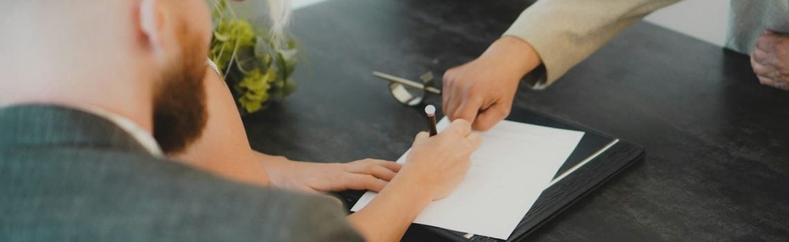 A woman signing a contract. Unfair Contract Terms